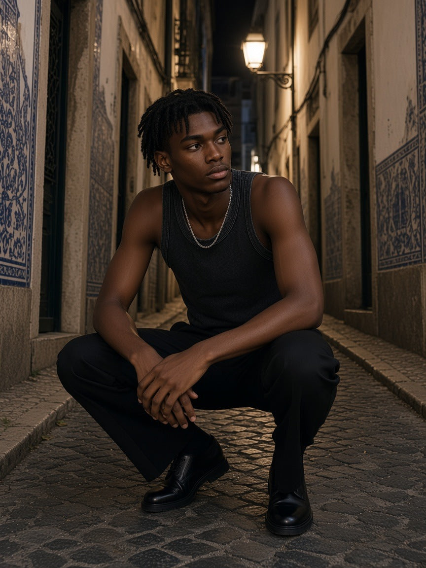 Man in the Marcel Afters Snow Washed Tank Top in Black in a tiled alley in Lisbon at night