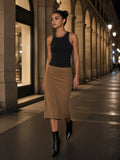 Woman in the Snow Washed Tank Top in Black tucked into a camel suede midi with pointed ankle boots, walking under the Rue de Rivoli arcade, Paris at 1am