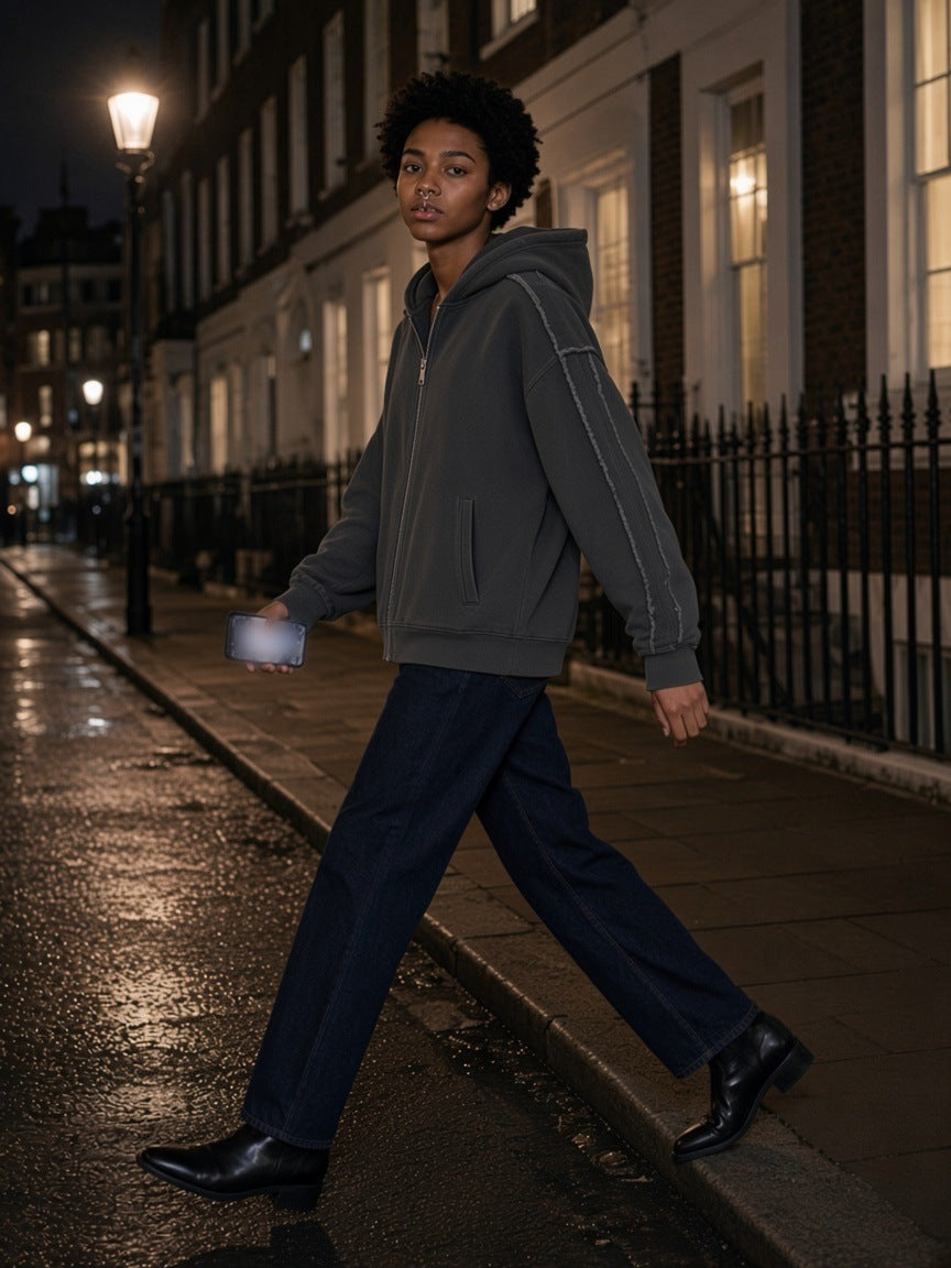 Woman in the Snow Washed Tape Raw Edge Zip Hoodie in Dark Gray stepping off a kerb on a wet London street at night