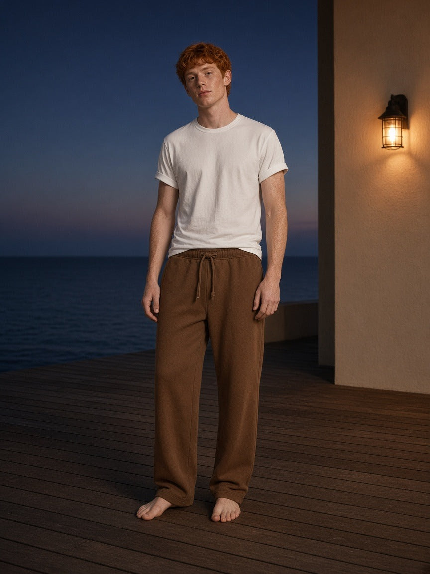 Man in the Marcel Afters Solid Color Straight-Leg Sweatpants in Coffee on a teak deck at a beach hotel in Malibu, Los Angeles, at blue hour