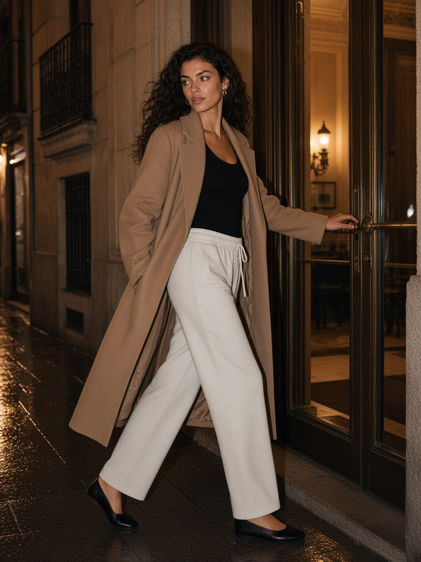 Woman in the Marcel Afters Solid Color Straight-Leg Sweatpants in Oat Gray in a palace hotel suite in Paris at night