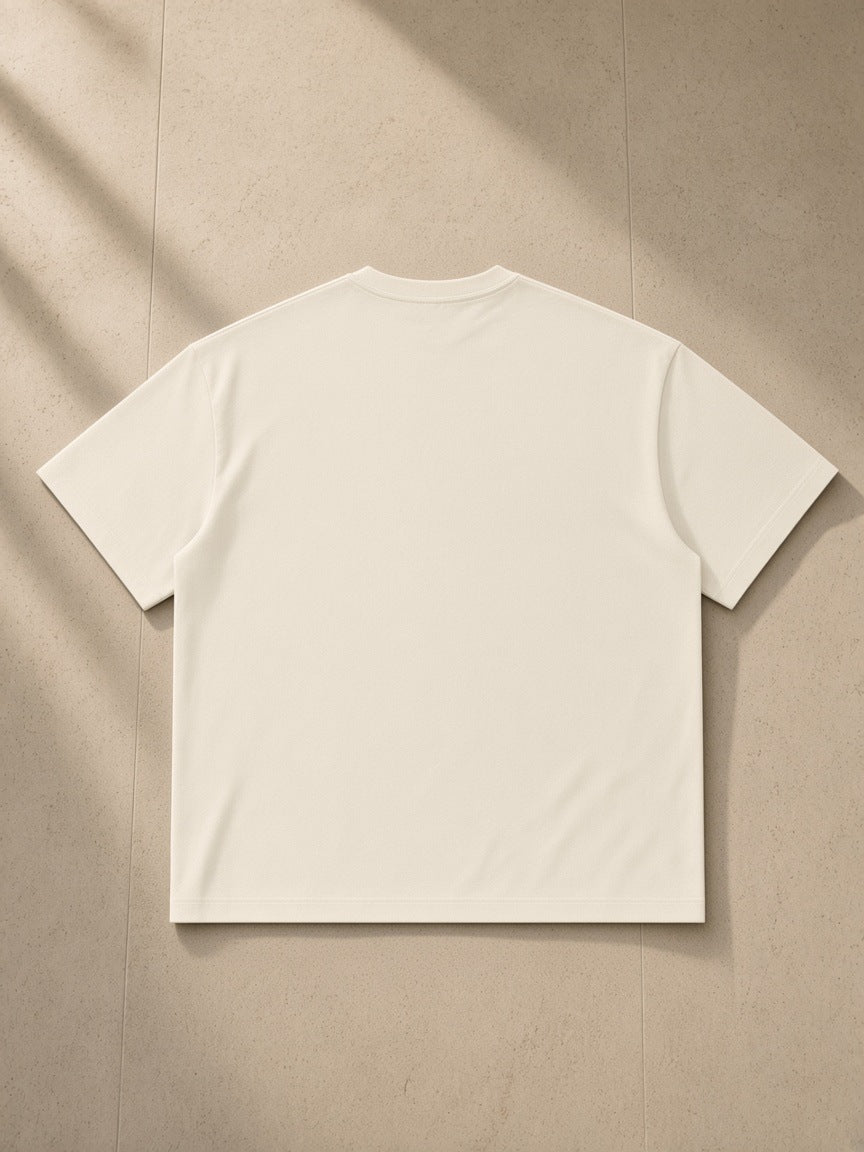 Sorona Boxy T-Shirt in Cream, laid flat on pale limestone, back view