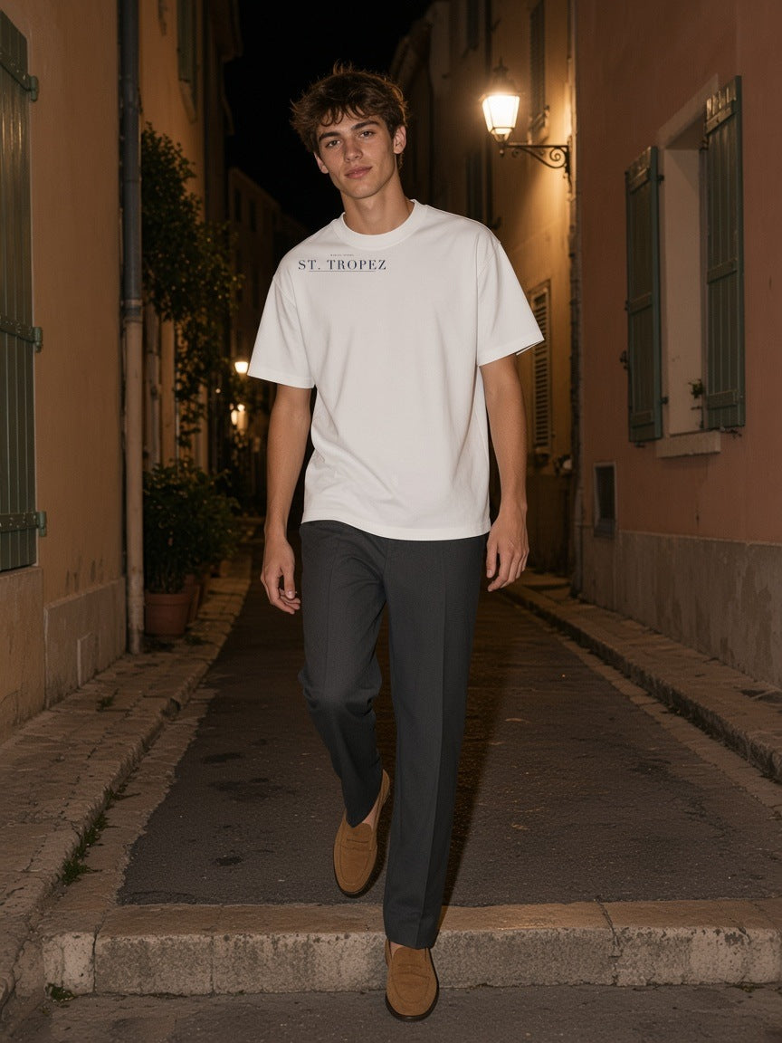Man in the St. Tropez Heavyweight Drop Shoulder T-Shirt in White on a villa terrace in St. Tropez at night