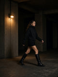 Woman in the Stand Collar Jacket in Black walking under Brutalist concrete in São Paulo at night