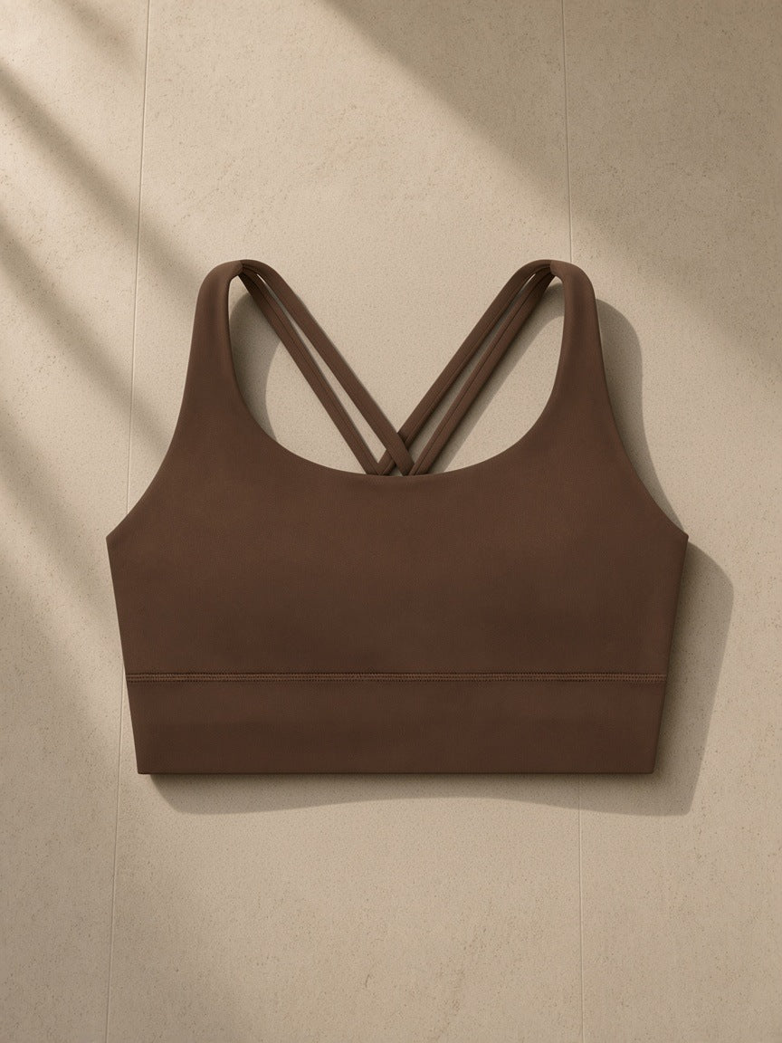 Strappy Criss-Cross Sports Bra in Chocolate Brown, laid flat on pale limestone