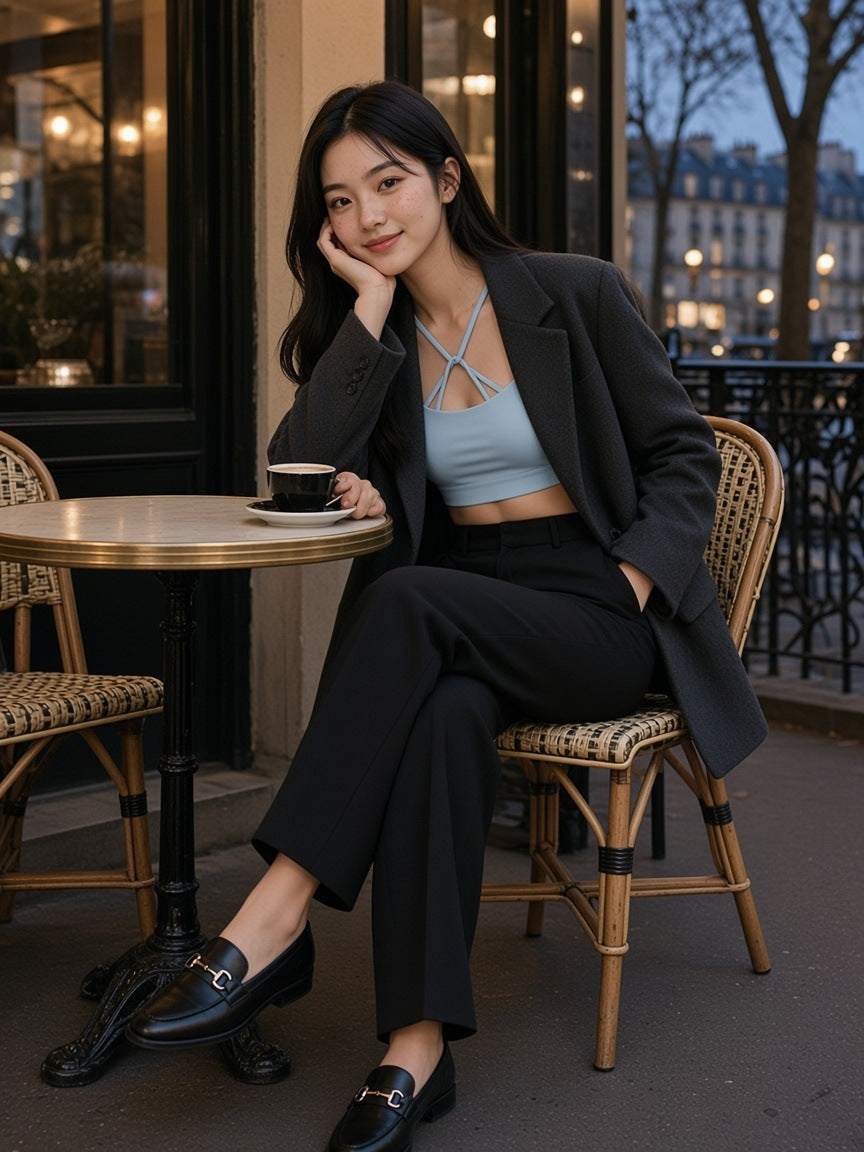 Woman in the Strappy Criss Cross Yoga Sports Bra in Light Blue under a charcoal blazer at a café table on Place Dauphine in Paris at blue hour