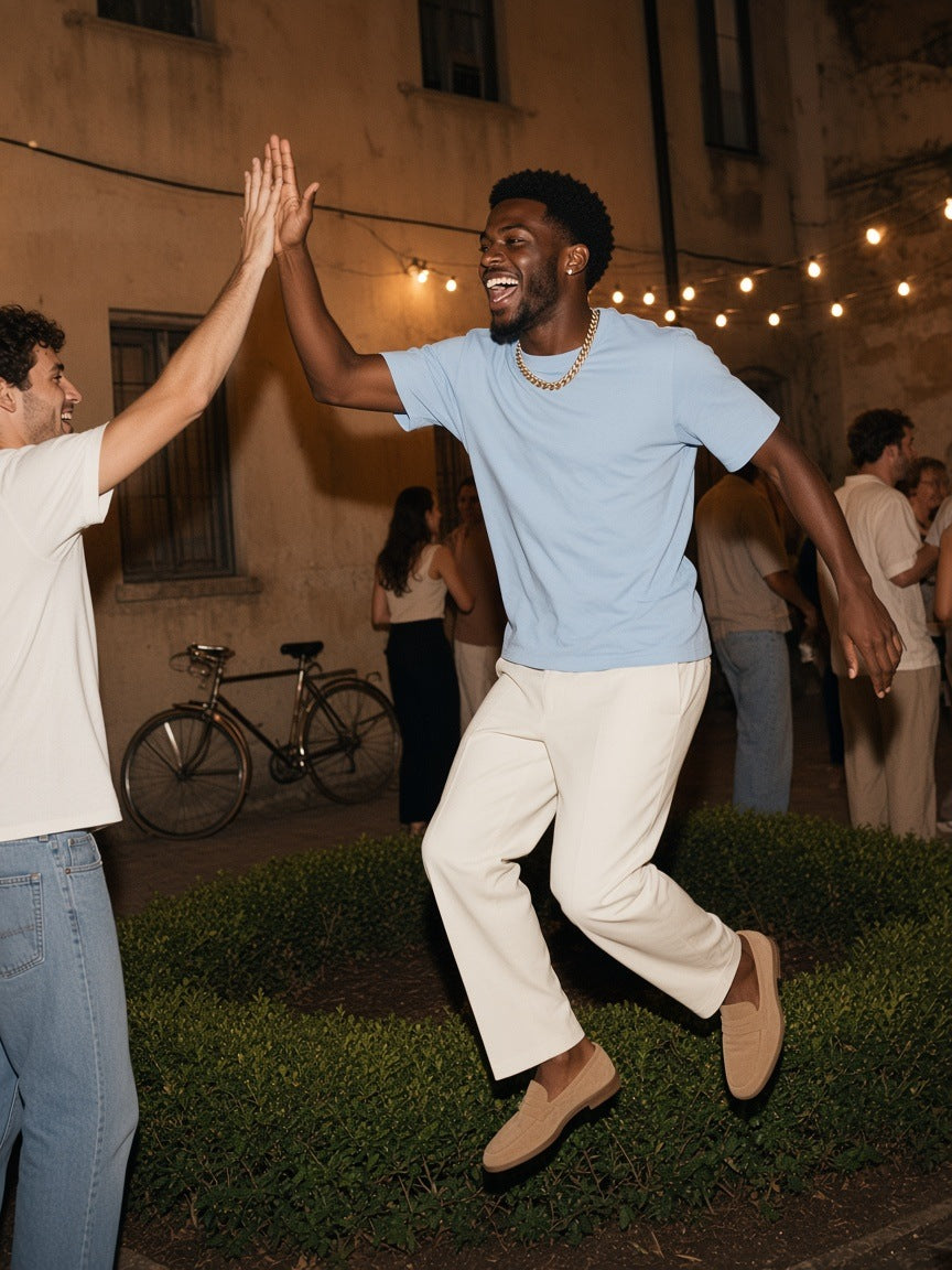 Man in the Sueded Cotton T-Shirt in Light Blue, jumping to high-five a friend at a Milan courtyard party at 1am