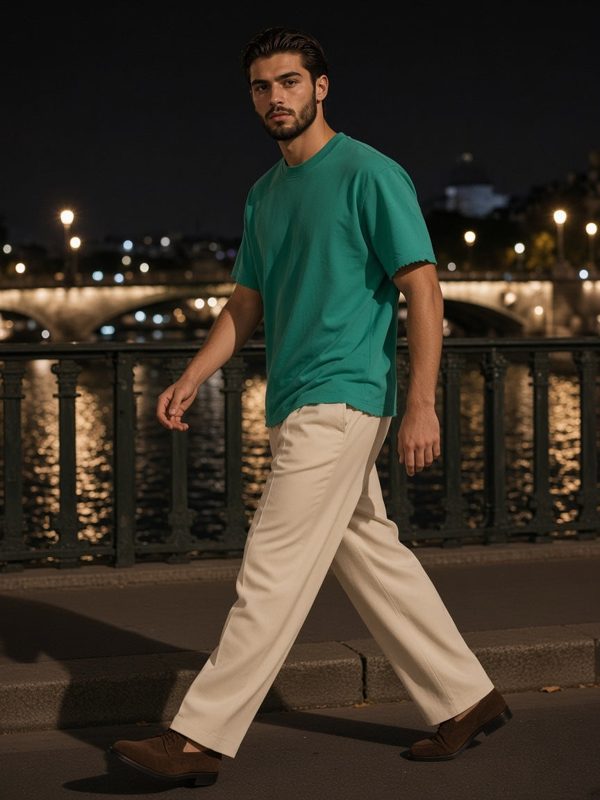 Man in the Sun Fade Raw Edge T-Shirt in Green walking the cobbles of Mercer Street, New York at night