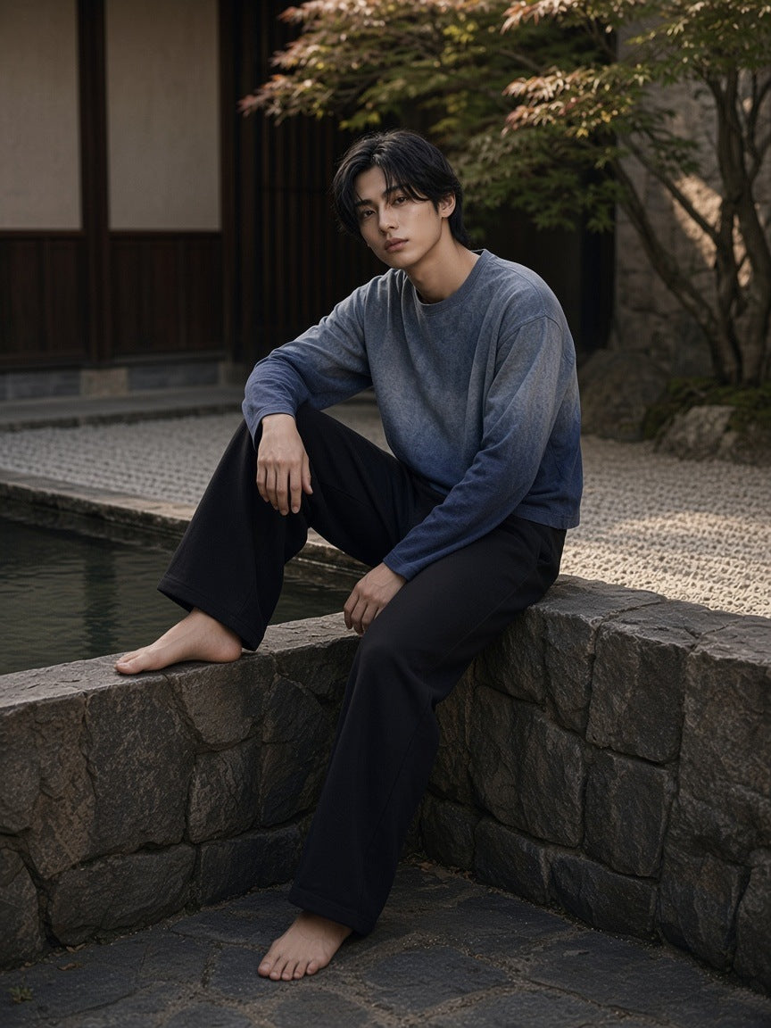 Man in the Sunfade Boxy Long Sleeve T-Shirt in Navy Blue beside a stone bath courtyard at a hotel in Tokyo by day