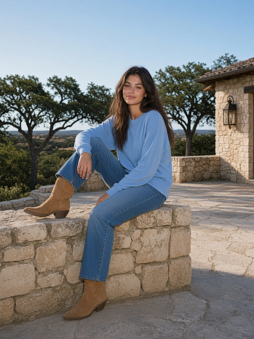 Woman in the Sunfade Boxy Long Sleeve T-Shirt in Sky Blue on the terrace of a ranch house in the Texas Hill Country by day
