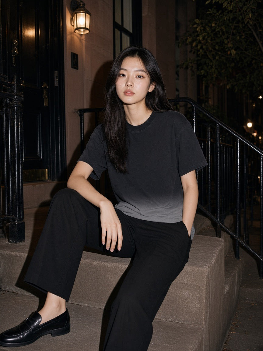 Woman in the Sunfade Vintage Washed T-Shirt in Black sitting on a townhouse stoop on the Upper East Side, New York at night