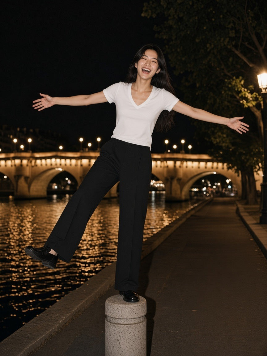 Woman in the Tencel Slim Fit V-Neck T-Shirt in White, balancing on a bollard by the Seine in Paris at 2am