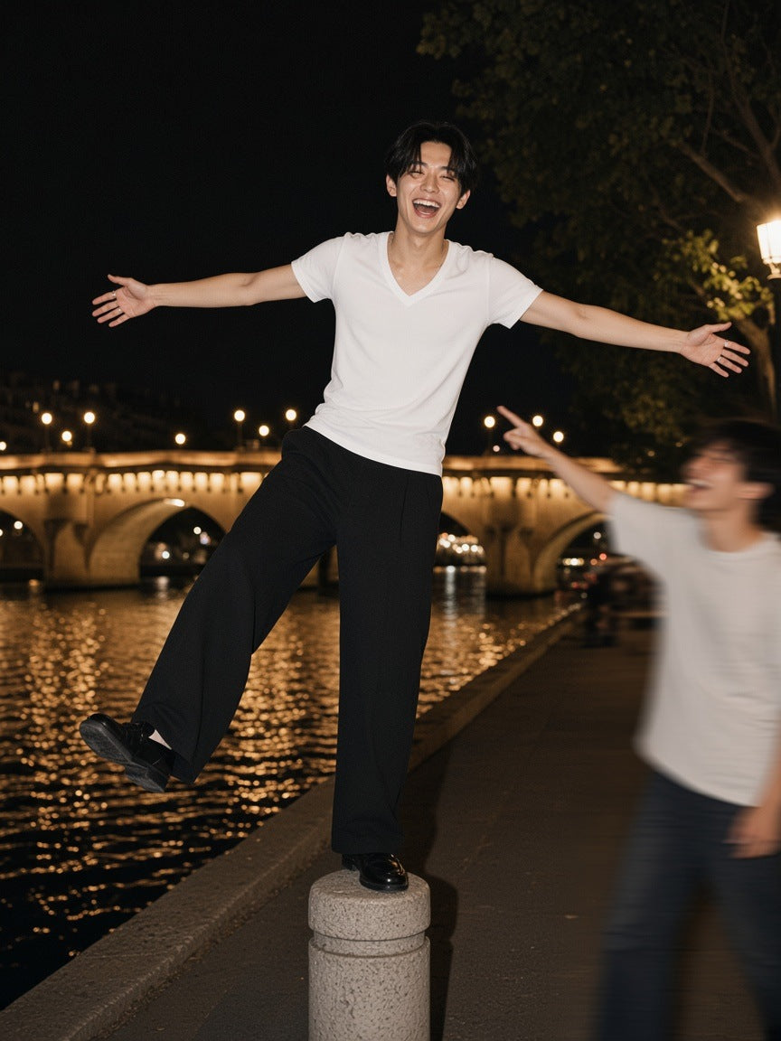 Man in the Marcel Afters Tencel Slim Fit V-Neck T-Shirt in White, balancing on a bollard by the Seine in Paris at 2am