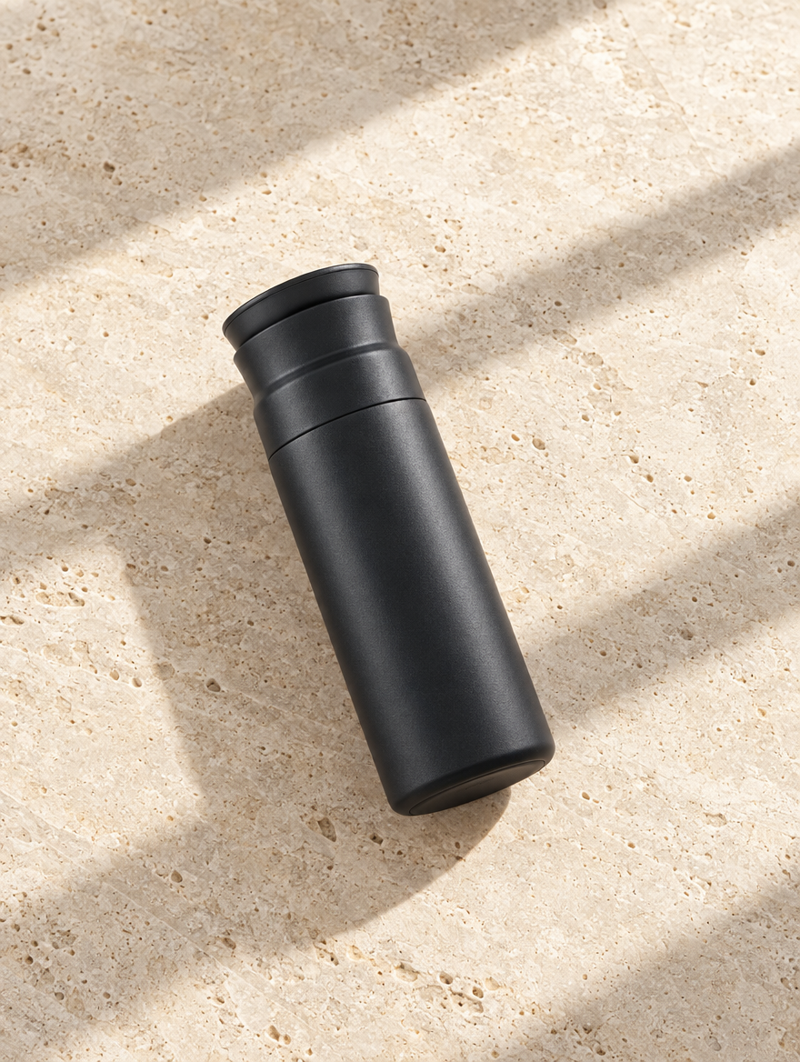 The Early Start Tumbler in Black, Marcel flat lay on pale limestone