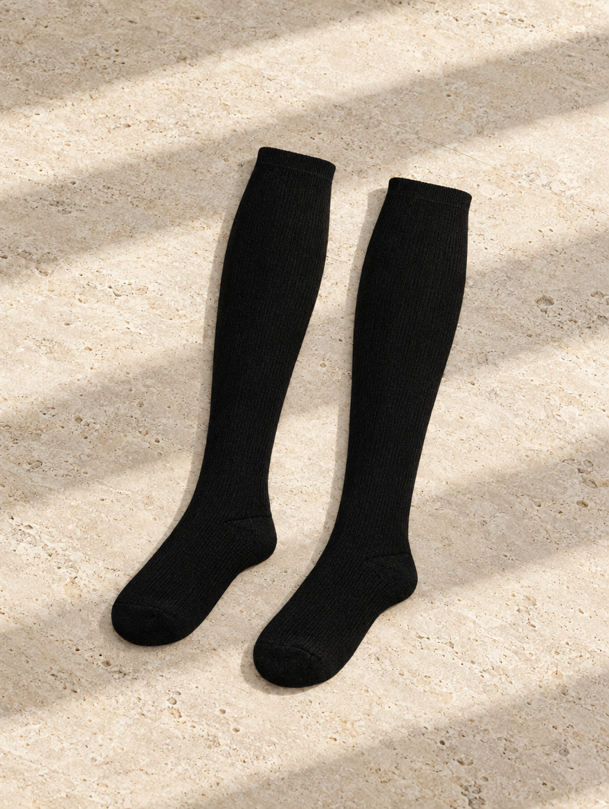 The Long Flight Sock in Black, Marcel flat lay on pale limestone