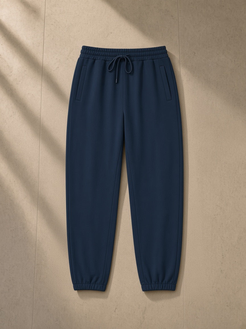 Loose Fit Tapered Joggers in Navy Blue, laid flat on pale limestone, tapered leg with elastic ankle cuffs