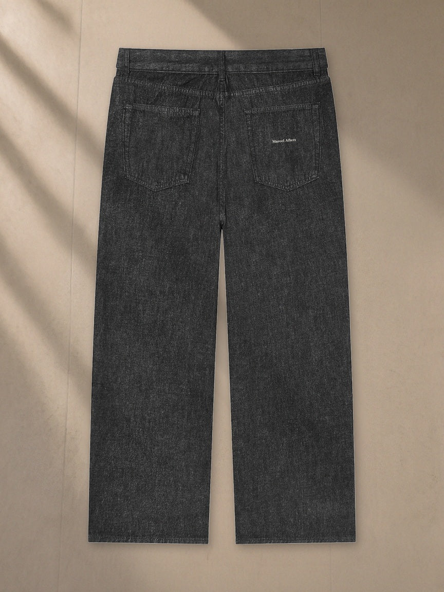 Unisex Vintage Wash Straight Leg Jeans in Black, laid flat on pale limestone, back view