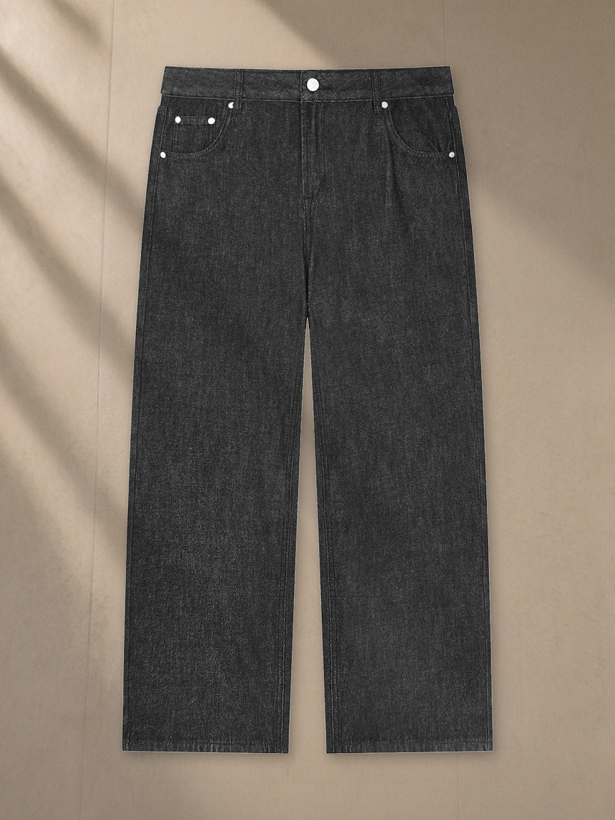 Unisex Vintage Wash Straight Leg Jeans in Black, laid flat on pale limestone