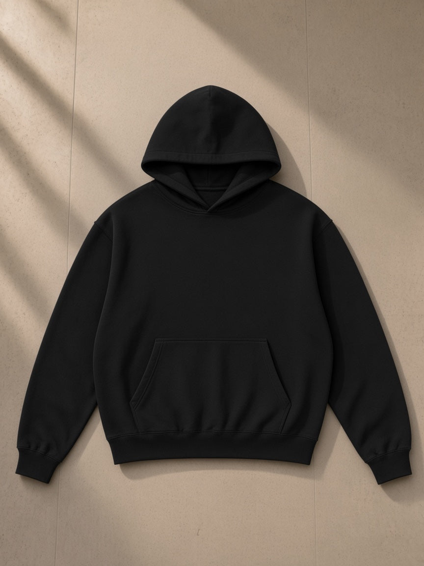 Unisex boxy darted sleeve hoodie in Black, laid flat on pale limestone, front view