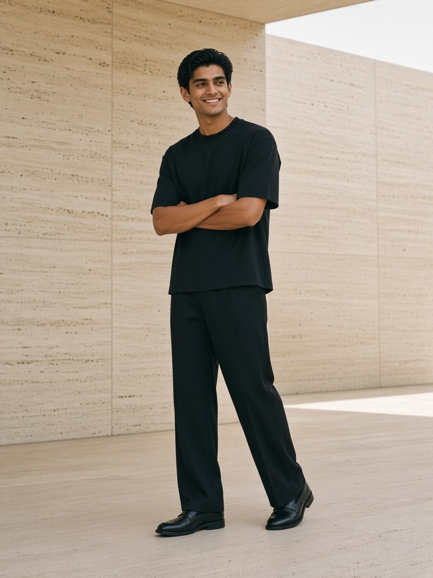 Man in the Boxy Drop Shoulder T-Shirt in Black in a travertine courtyard in the morning