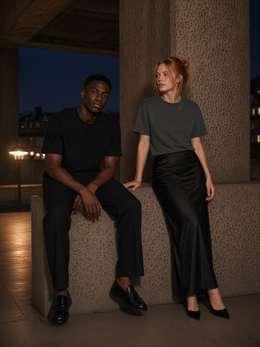 Two people in the Marcel Afters Boxy Drop Shoulder T-Shirt in Black and Dark Gray on a Brutalist walkway in London at night