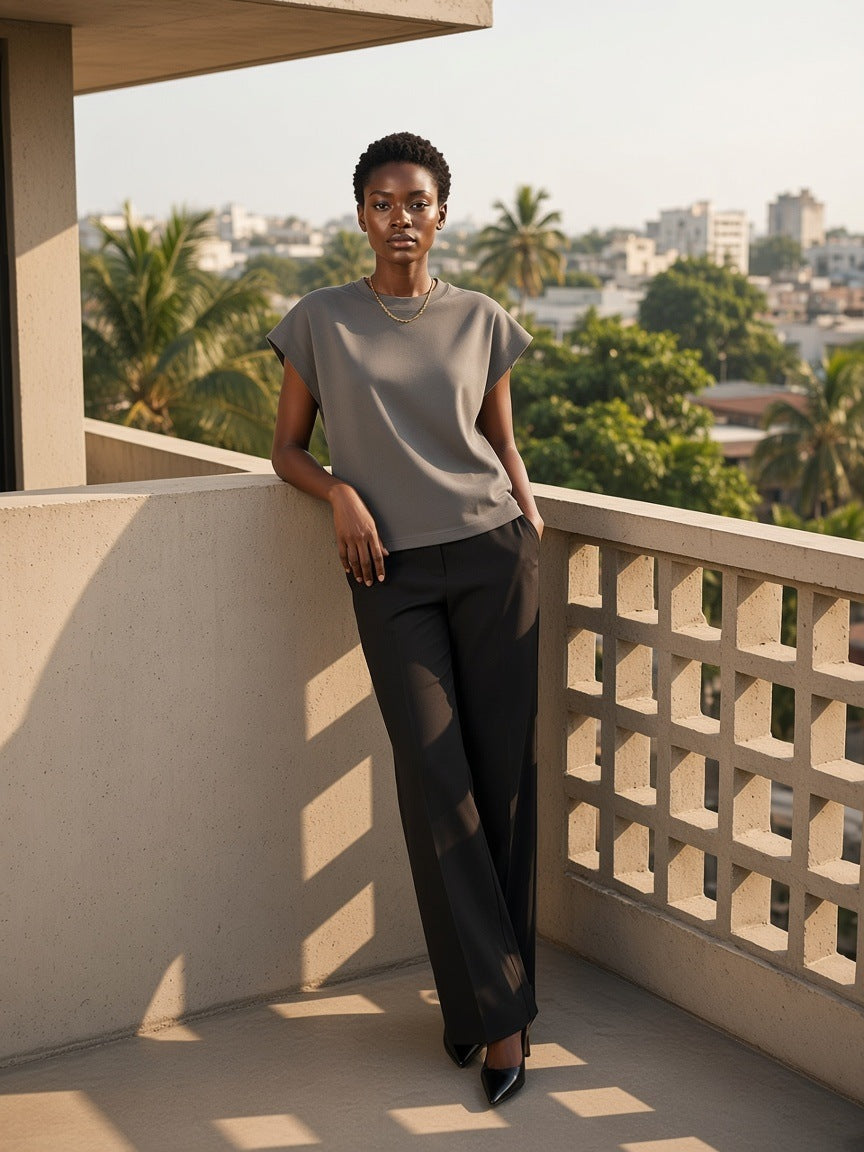 Woman in the Boxy Raw Edge T-Shirt in Gray on a concrete balcony in Lagos in the morning