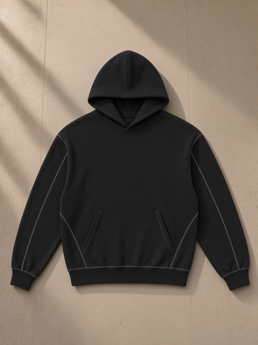 Unisex contrast-stitched boxy fleece hoodie in Black, laid flat on pale limestone, front view