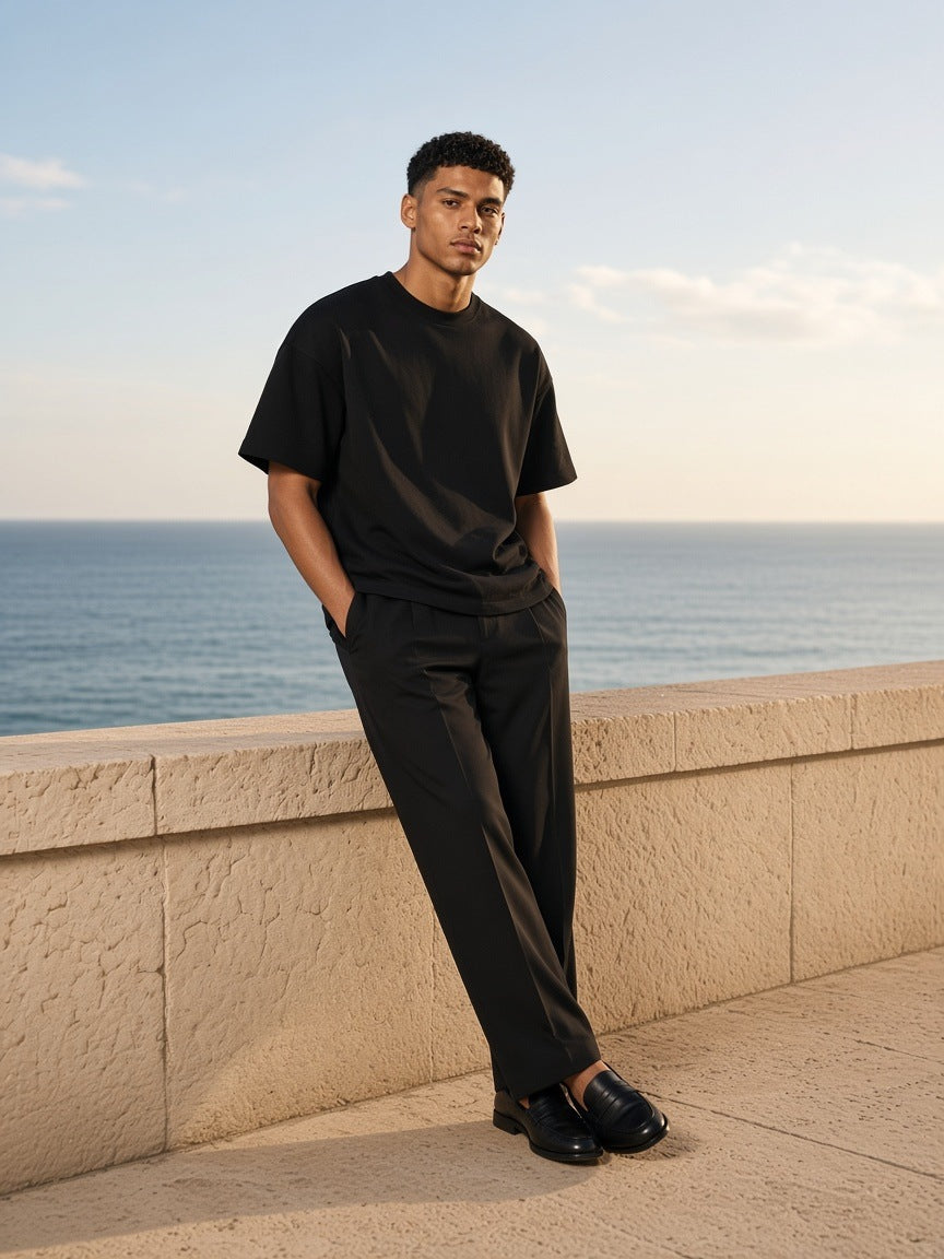 Man in the Heavyweight Boxy Raw Edge T-Shirt in Black on a limestone sea terrace near Lisbon in the morning