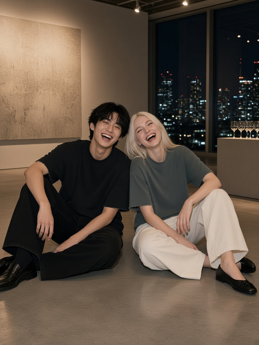 Two people in the Marcel Afters Heavyweight Boxy Raw Edge T-Shirt in Black and Gray Blue in a Tokyo gallery at night