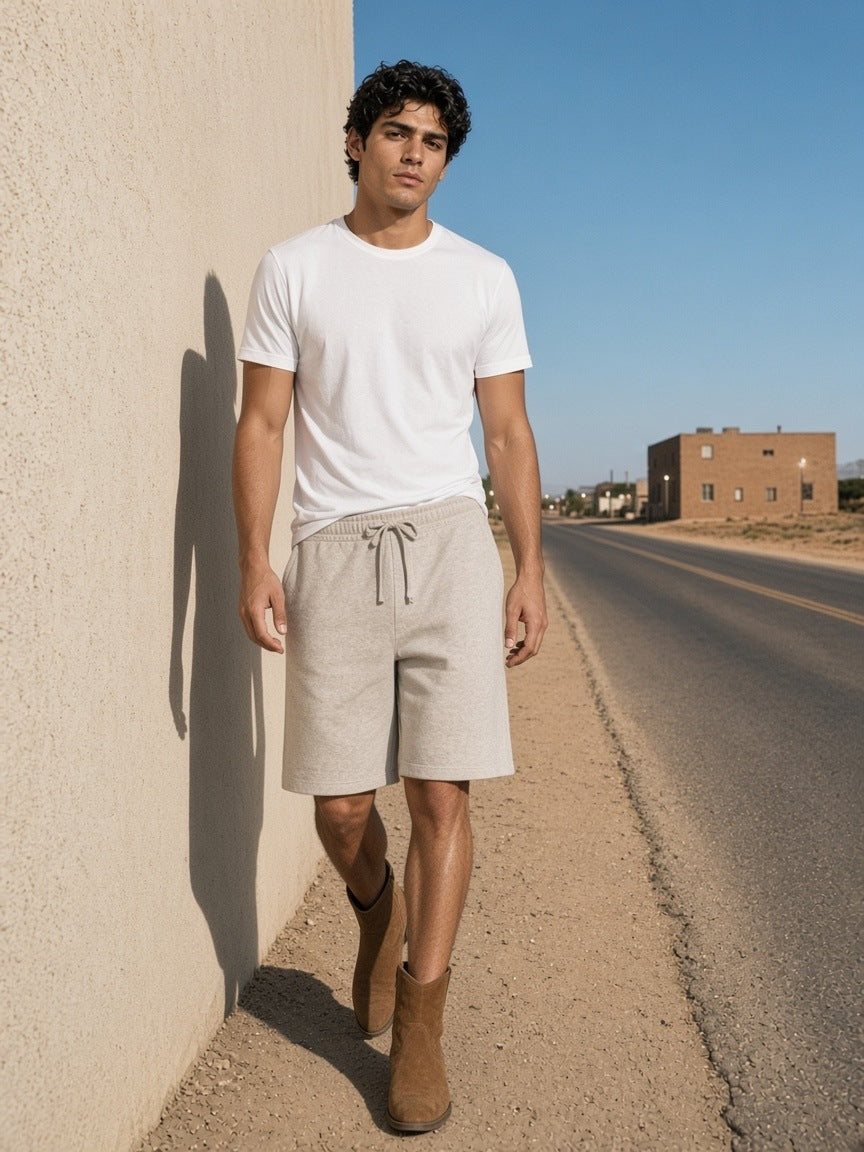 Man in the Heavyweight Shorts in Oat Gray walking by an adobe wall in Marfa, Texas in the morning