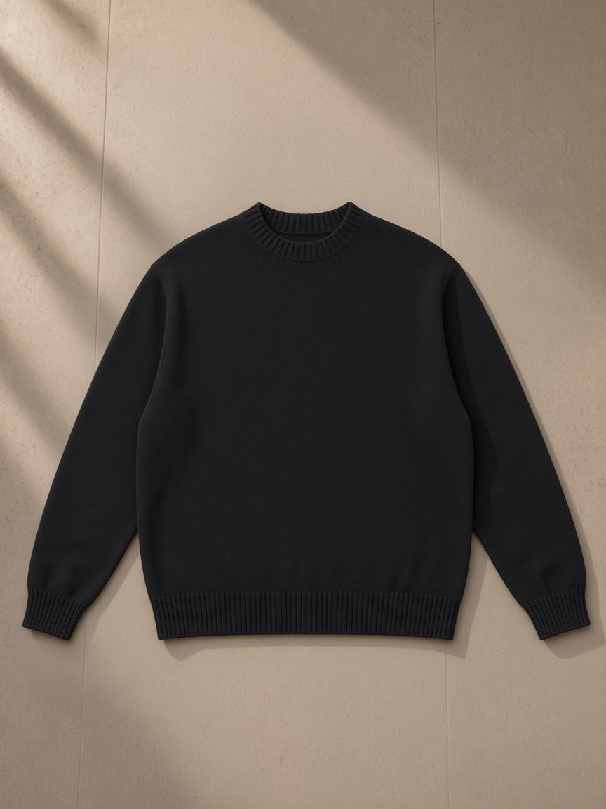 Unisex knitted round neck oversize sweatshirt in Black, laid flat on pale limestone, front view