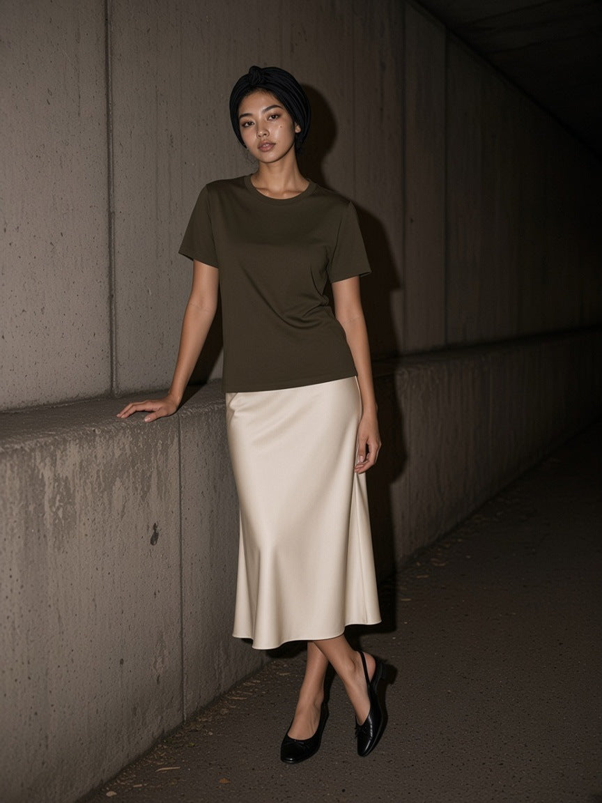 Woman in the Lightweight Crewneck T-Shirt in Coffee and a satin midi skirt at a concrete tunnel exit in London at night
