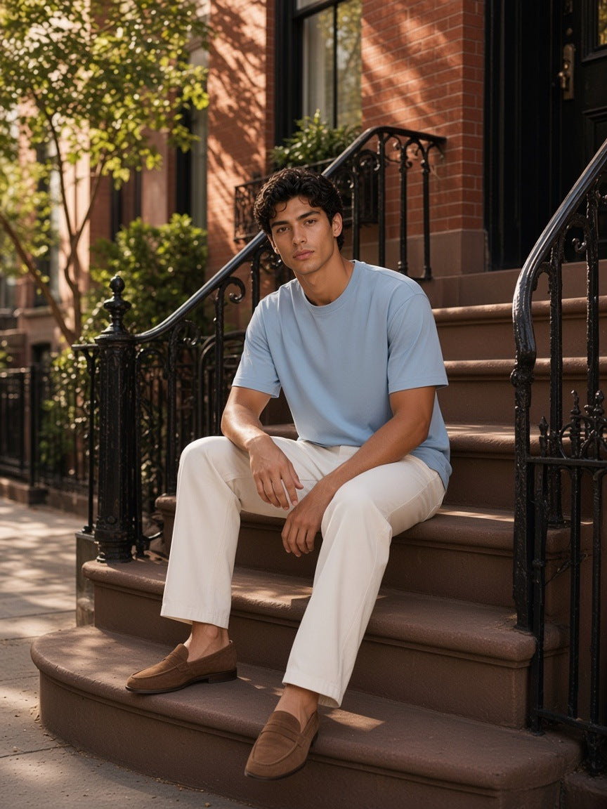 Man in the Lightweight Oversized T-Shirt in Haze Blue standing by a brownstone stoop in the West Village, New York in the morning