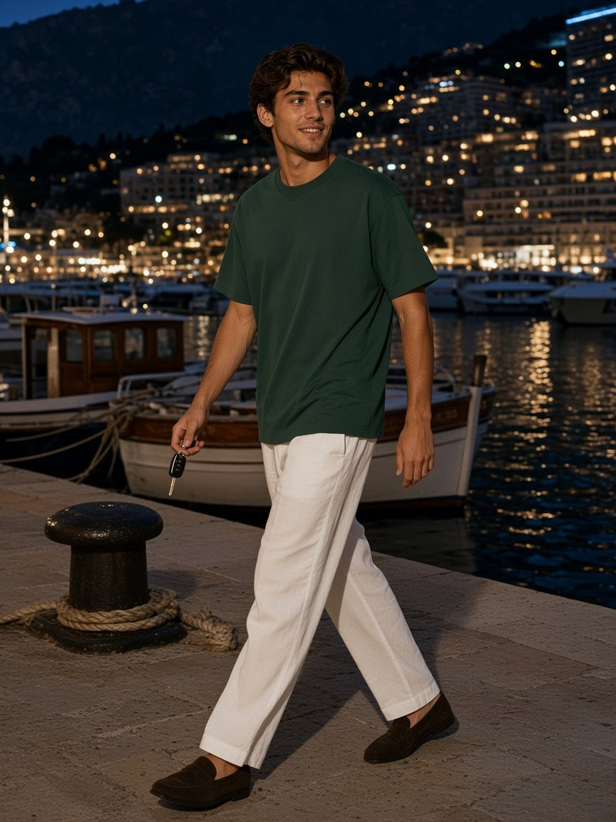 Two people in the Marcel Afters Loose Drop Shoulder T-Shirt in Black and Retro Green on a yacht deck in Monaco harbour at night