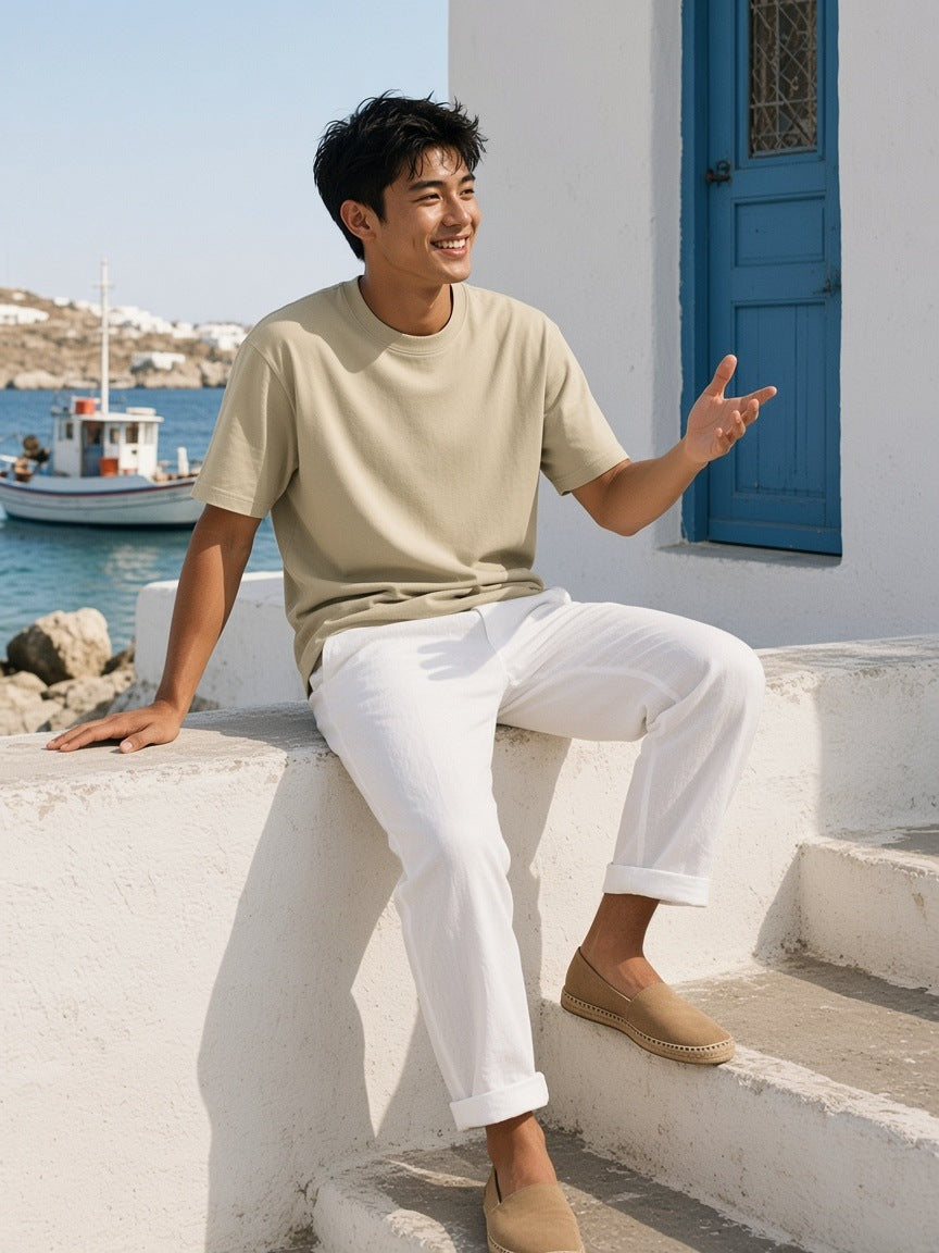 Woman in the Loose Drop Shoulder T-Shirt in Pale Khaki walking down a whitewashed stair in Mykonos in the morning