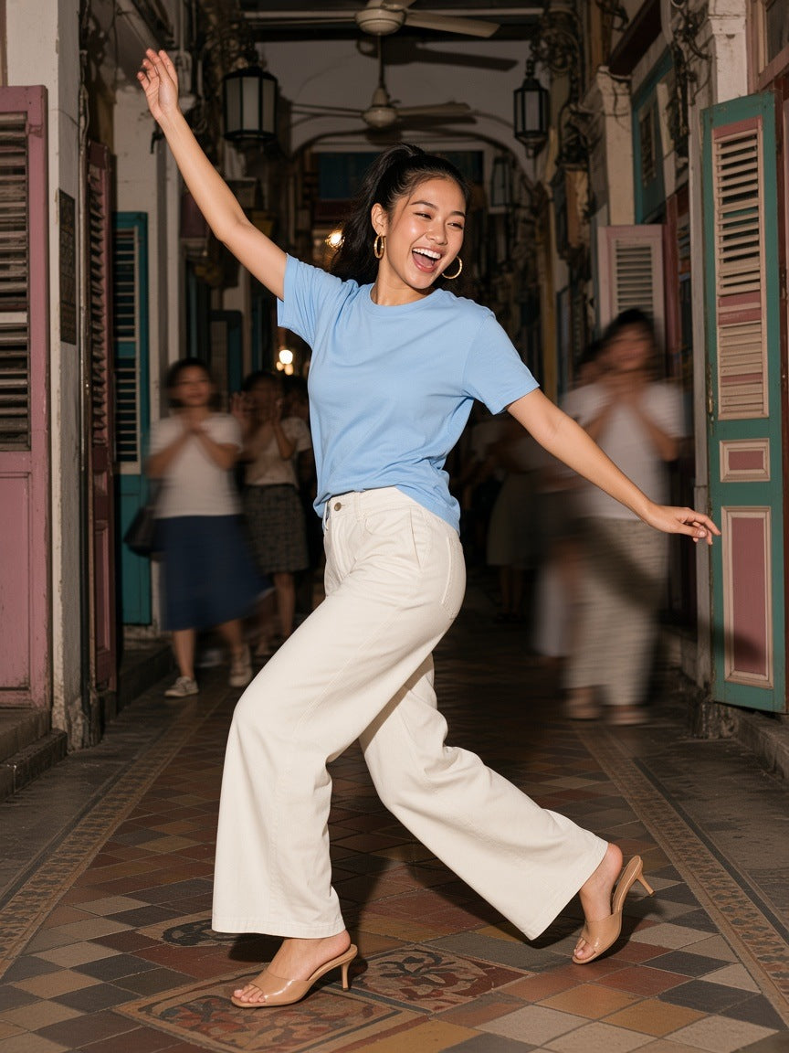 Woman in the Marcel Afters Mid-Weight Cotton T-Shirt in Sky Blue at a rooftop hotel pool in Singapore at night
