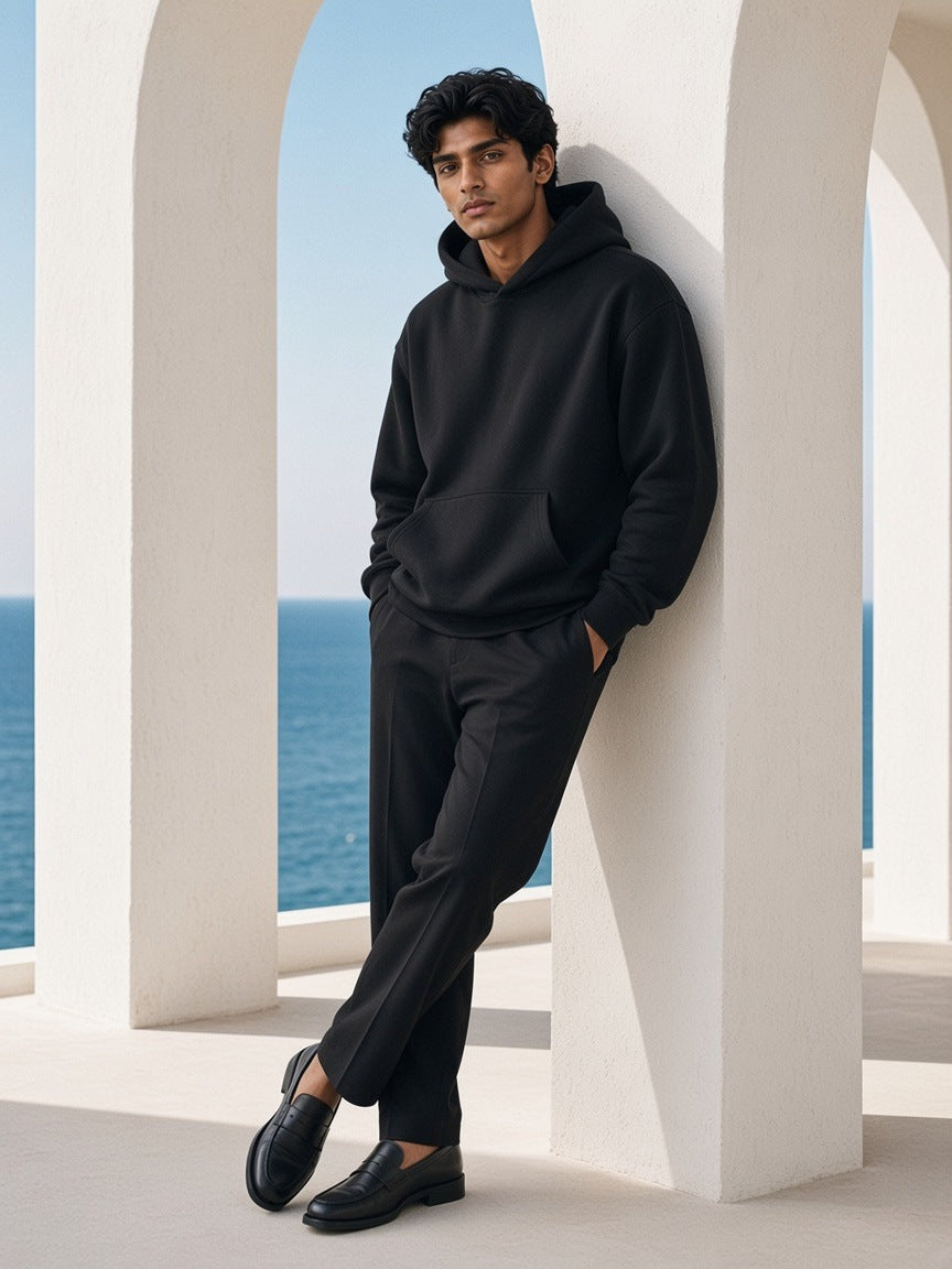 Man in the Oversized Heavyweight Hoodie in Black, under a whitewashed colonnade in Mykonos in the morning
