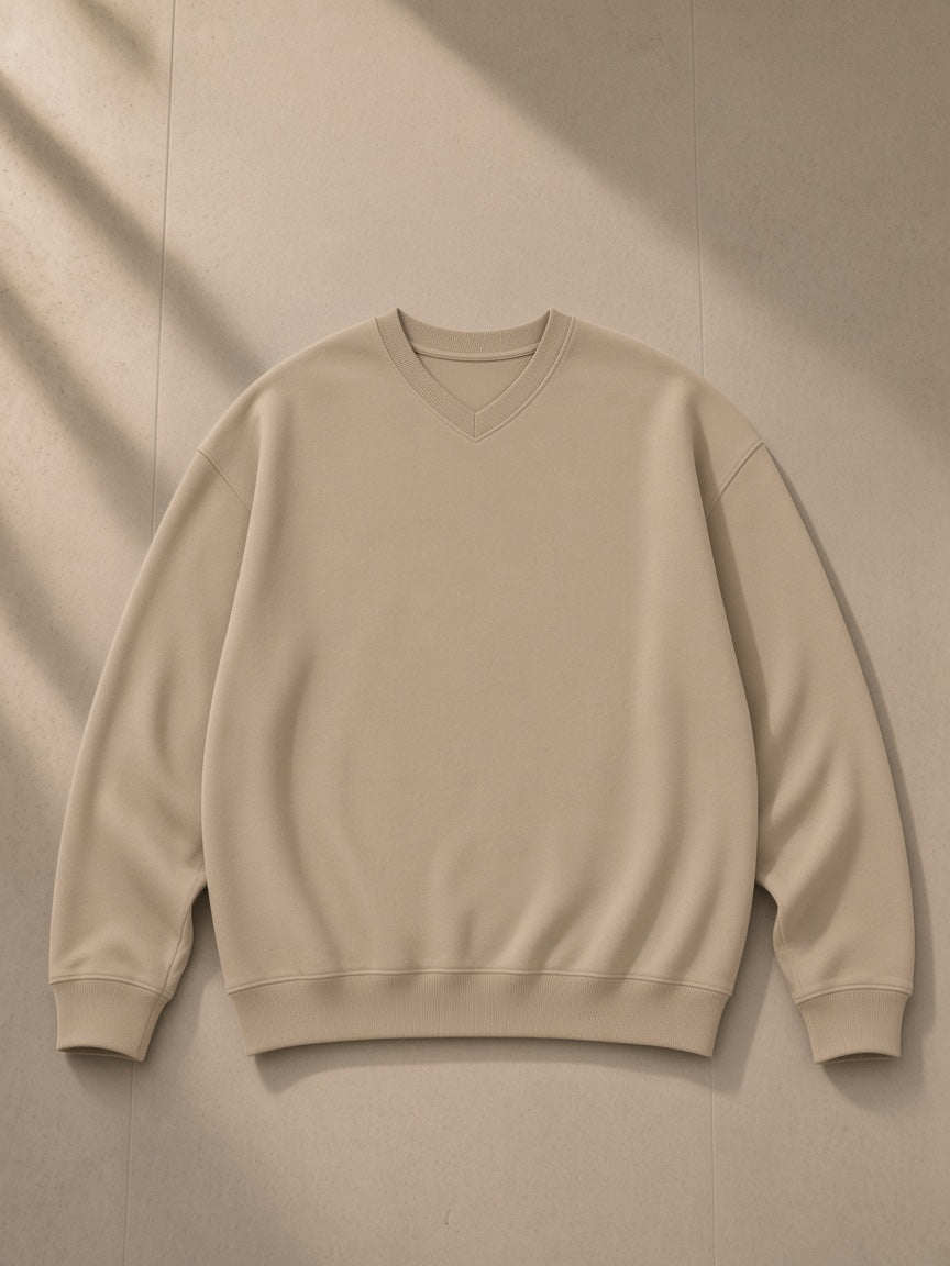 Unisex oversized v-neck sweatshirt in Khaki, laid flat on pale limestone, front view