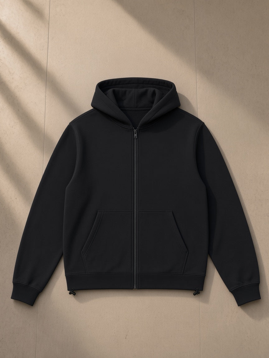 Unisex paneled full zip hoodie in Black, laid flat on pale limestone, front view