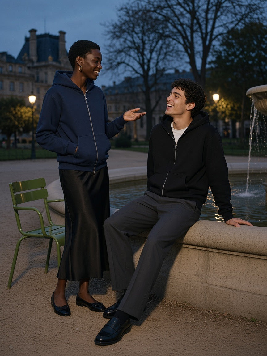 Two people in the Marcel Afters Regular Fit Full Zip Hoodie in Black and Navy Blue by the Tuileries fountain in Paris at blue hour