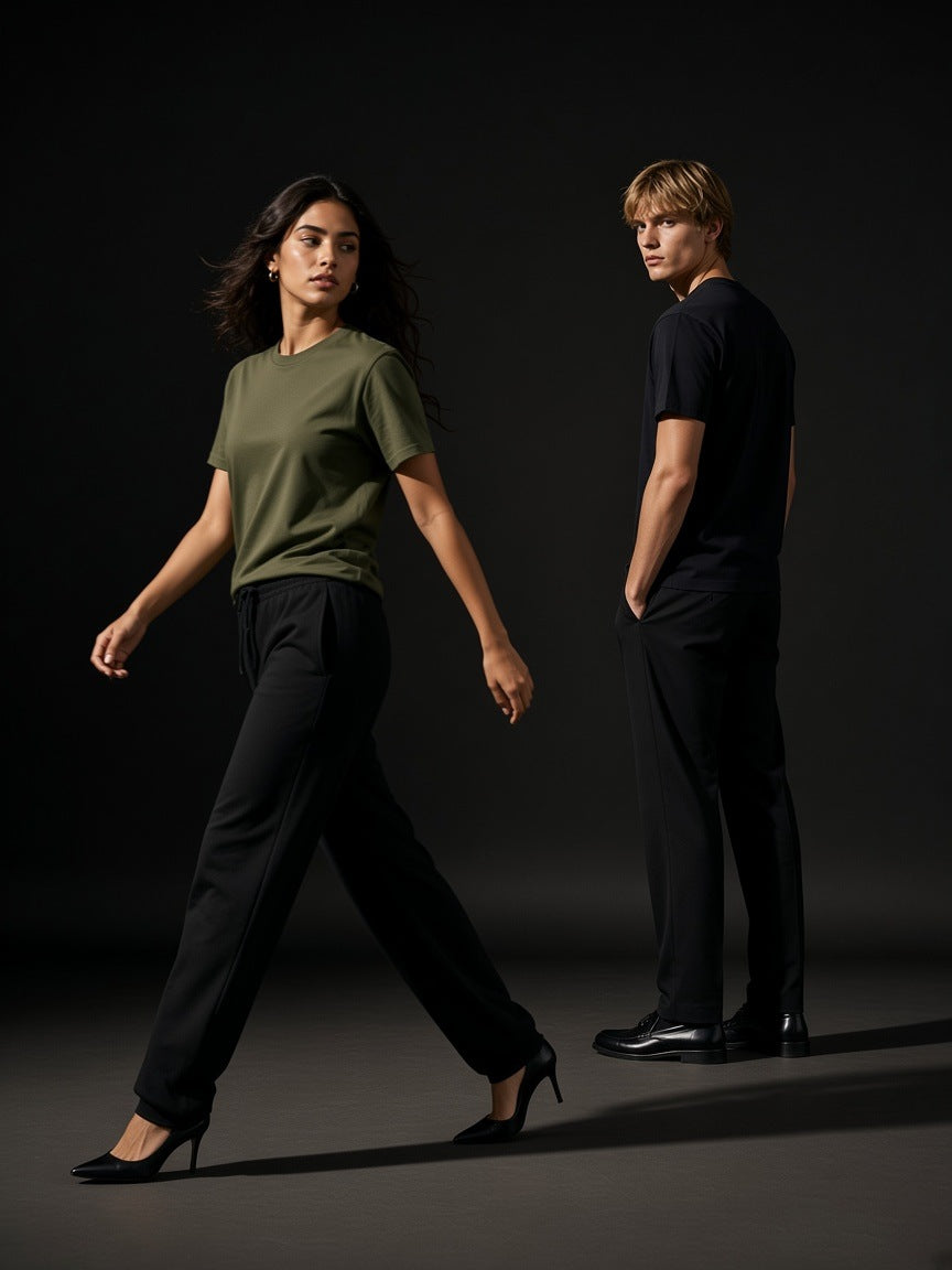 Two people in the Marcel Afters Seamless Cotton T-Shirt in Army Green and Black, a woman walking in heels, a man looking back, charcoal studio