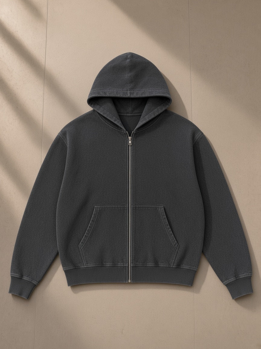 Unisex snow wash oversized zip-up hoodie in Black, laid flat on pale limestone, front view
