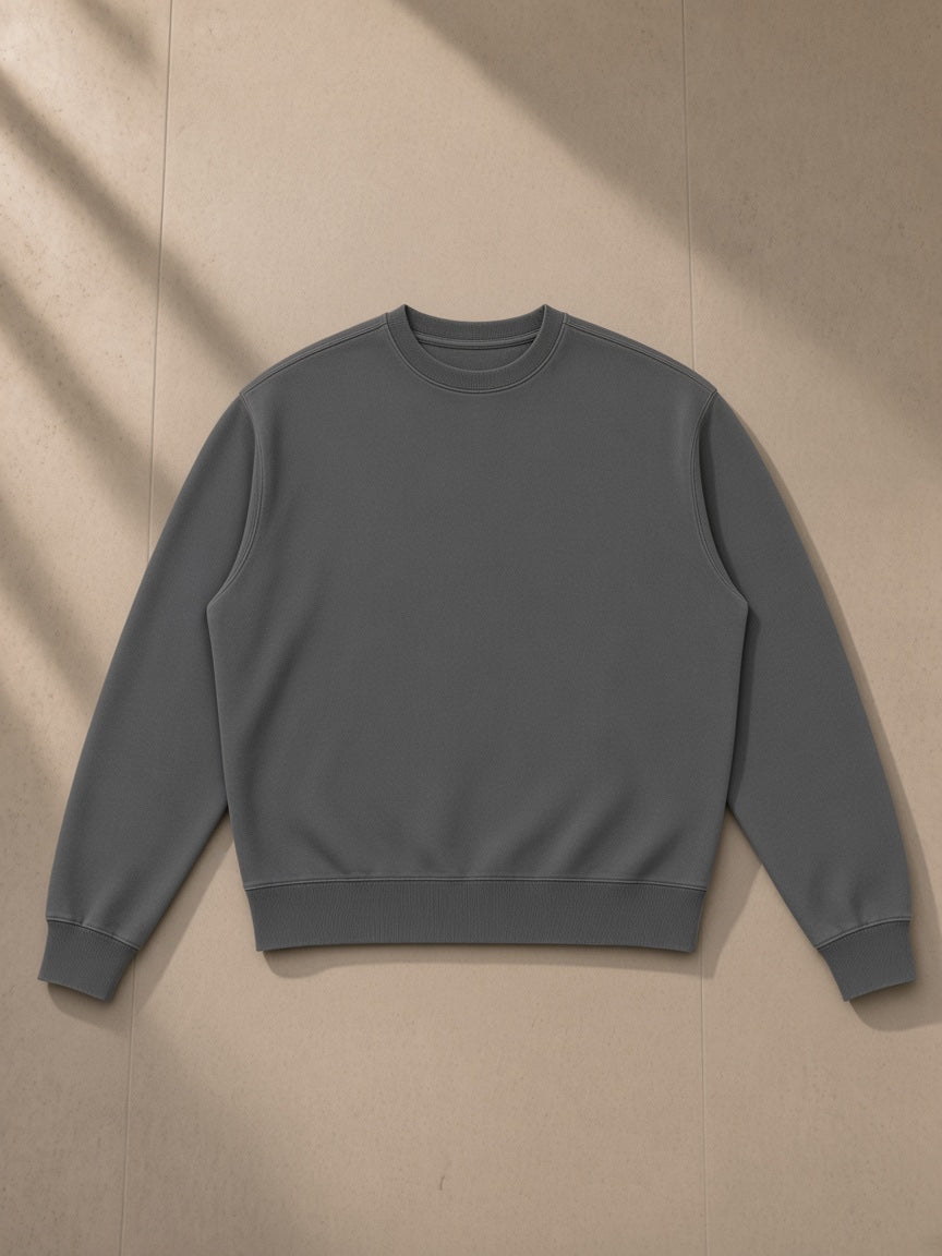 Unisex vintage wash crewneck sweatshirt in Dark Gray, laid flat on pale limestone, front view
