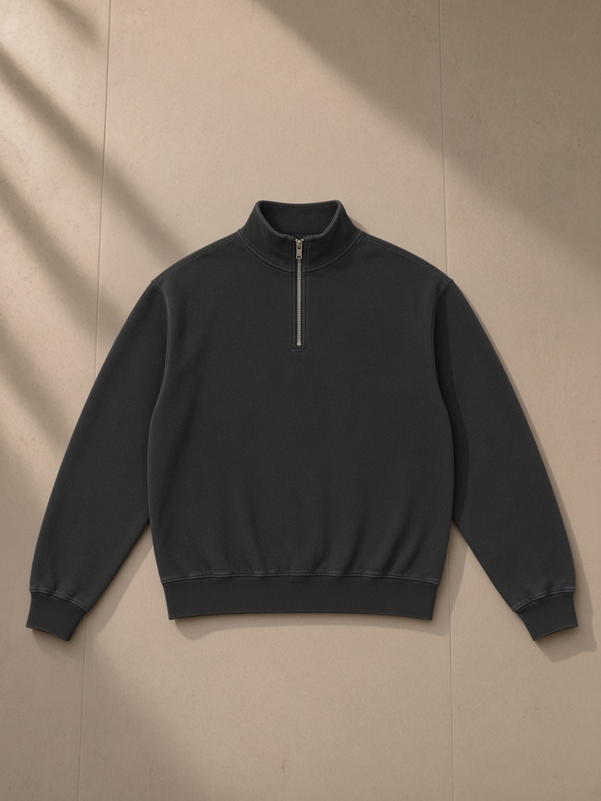 Unisex vintage wash fleece quarter zip sweatshirt in Black, laid flat on pale limestone, front view