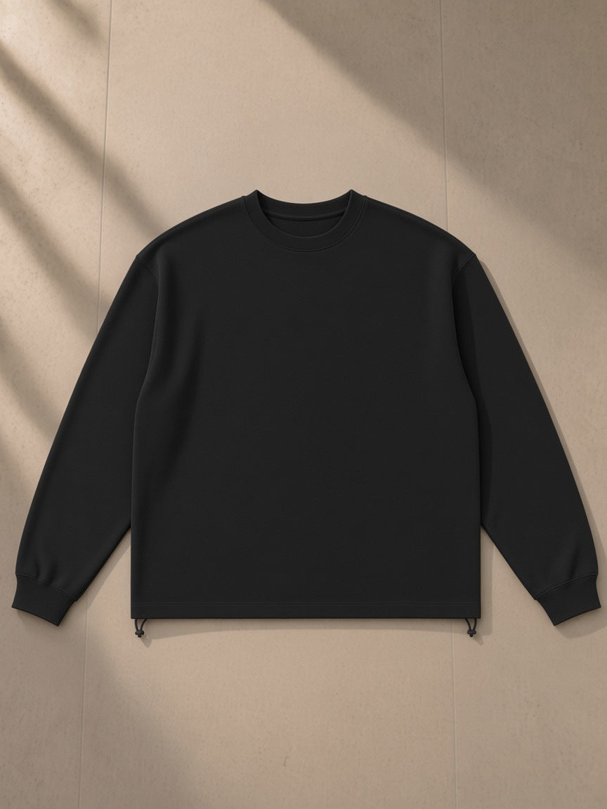 Heavyweight oversized boxy sweatshirt in Black, laid flat on pale limestone, front view
