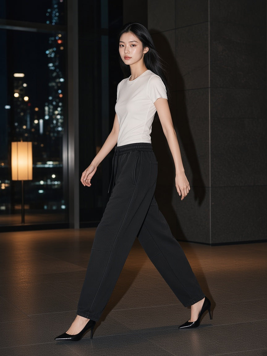 Woman in the Vintage Wash Barrel Leg Fleece Sweatpants in Black walking through a stone hotel lobby in Tokyo at night