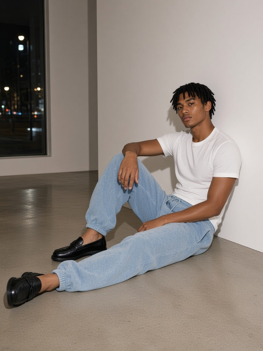 Man in the Vintage Wash Barrel Leg Fleece Sweatpants in Light Blue seated against a gallery wall in Hannam-dong, Seoul at night
