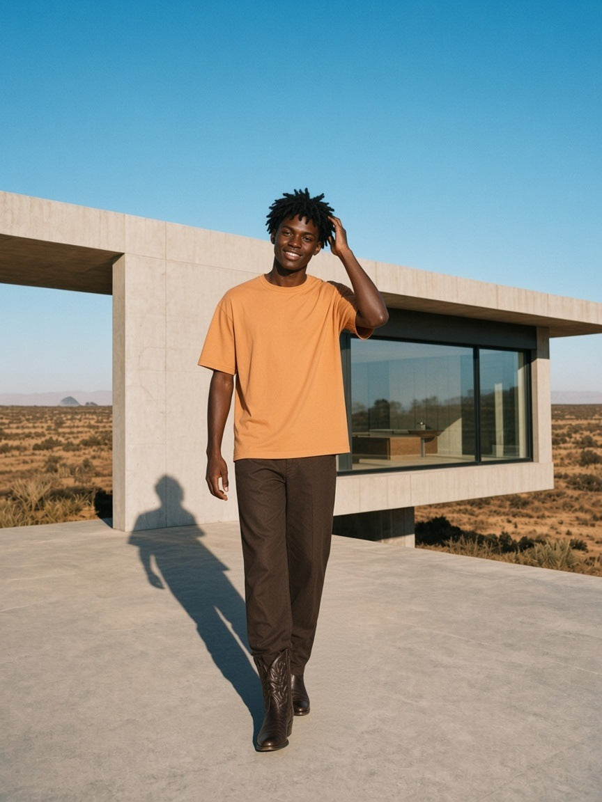 Man in the Vintage Wash Boxy T-Shirt in Apricot outside a concrete ranch house in Marfa, Texas in the morning