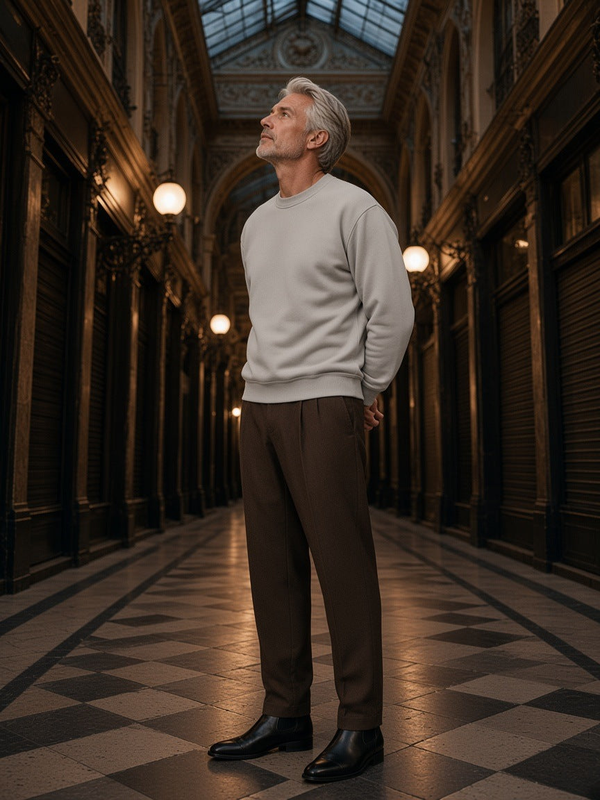 Man in the Vintage Wash Fleece Sweatshirt in Light Gray looking up in a glass-roofed Paris arcade at night