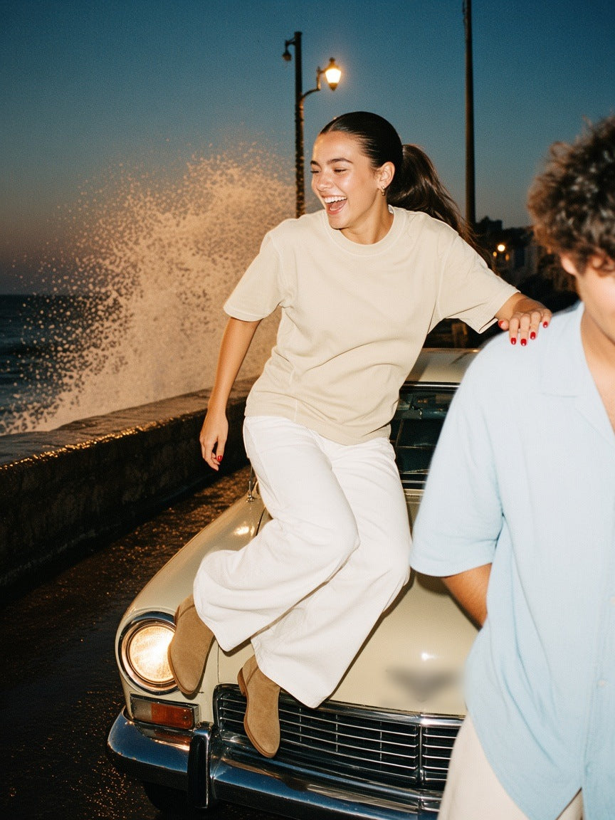 Woman in the Vintage Wash Paneling T-Shirt in Apricot, hopping off a vintage car on the Havana seafront at 1am
